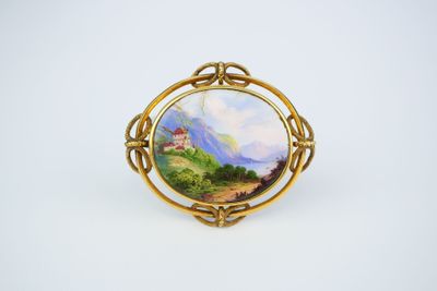 a gold broochle with a painting of a castle on it