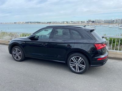 Le SUV Audi noir est garé sur le bord de la route, près de l'eau.