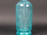 une vieille bouteille en verre bleu munie d'un robinet en métal sur le dessus