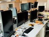 trois écrans d'ordinateur posés sur un bureau dans un bureau