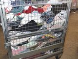 a metal cart filled with lots of clothes in a warehouse