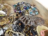a wooden bowl filled with assorted jewelry on a table