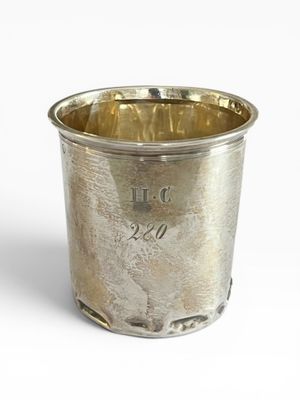 une tasse en argent posée sur une surface blanche