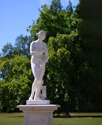 a statue of a woman holding a dog in a park