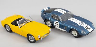 deux voitures jouets assises l'une à côté de l'autre sur une surface blanche