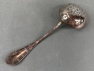 silver spoon with black dots on it sitting on a gray surface