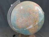 un petit globe terrestre posé sur un socle, sur fond gris