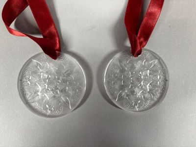 two silver christmas ornaments with red ribbon on a white surface