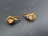 deux paires de boucles d'oreilles en or et diamants posées sur un fond noir