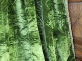 a bed with a green blanket on top of it next to a dresser