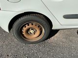 une petite voiture blanche avec un pneu crevé dans la rue