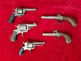 quatre vieux revolvers sur une surface en velours rouge