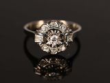 an antique engagement ring with a center stone surrounded by small diamonds