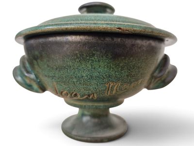 un vase vert avec un couvercle sur fond blanc