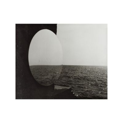 black and white photograph of a view of the ocean through a round window