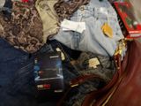 a suitcase full of clothes and a handbag sitting on the floor