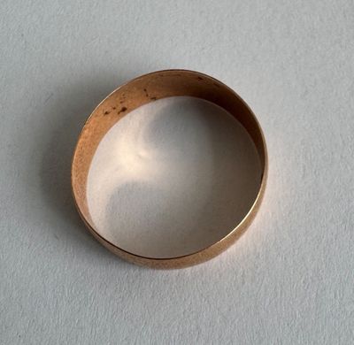 a gold ring on a white surface with a shadow on it