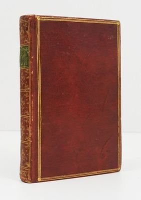un vieux livre à la couverture rouge posé sur une surface blanche
