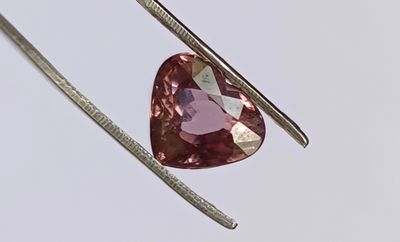 un gros plan sur un diamant rose en forme de cœur monté sur un crochet en argent