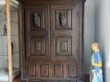 une armoire en bois placée dans un coin de la pièce, près d'une fenêtre