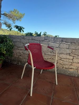 a red chair sitting on a patio next to a stone wall