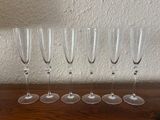 six empty wine glasses lined up on a wooden table
