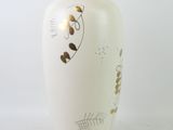 a white vase with gold designs on it on a white surface