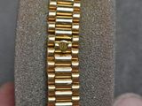 someone is holding a watch in their hand with a gold bracelet