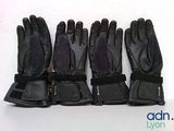five pairs of black leather gloves lined up against a white wall