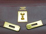 the handle of a brown leather bag with a brass plate