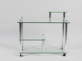 une table en verre transparent avec deux étagères, montée sur roulettes