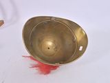 a metal bowl with a red feather on the floor