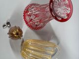 a red glass vase with a gold handle on a white surface