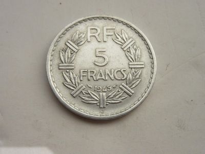 une pièce de 5 francs posée sur une surface blanche