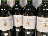 six bottles of red wine lined up on a table with a price tag