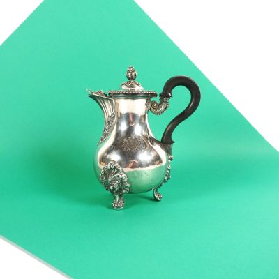 une théière en argent posée sur une surface verte