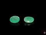 a pair of green emeralds on a black surface