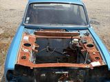 a blue car with a rusted hood sitting in a parking lot