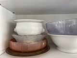several bowls and bowls are stacked on a shelf in a cabinet