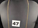 un gros plan d'un collier porté par un mannequin, sur lequel figure le chiffre 47