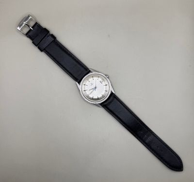gros plan d'une montre sur une surface blanche avec un bracelet noir