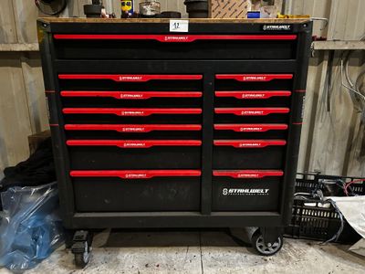 une armoire à outils noire avec des tiroirs rouges dans un garage