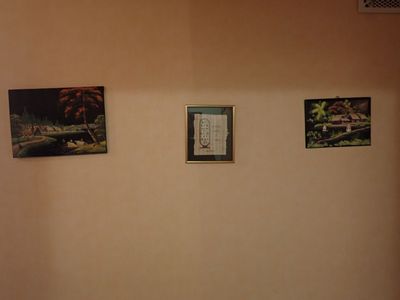 une photo d'une salle de bains avec des toilettes et des tableaux accrochés au mur