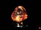 a close up of a heart shaped orange diamond on a black surface