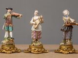 three figurines of men playing musical instruments on a table