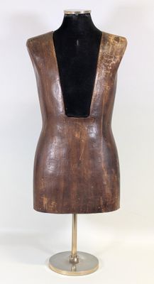 une image représentant un mannequin en bois posé sur un socle, sur fond blanc