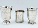 trois tasses en argent posées l'une à côté de l'autre sur une surface blanche