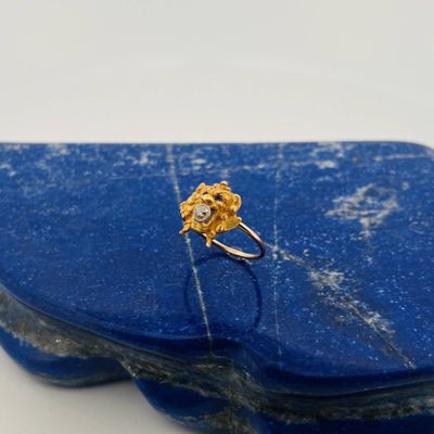 gold plated ring with a single stone in the middle of it on a blue stone