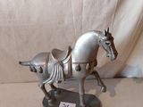 statue d'un cheval sellé, posée sur un socle, sur fond blanc