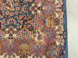 an antique persian rug with a blue background and a floral design